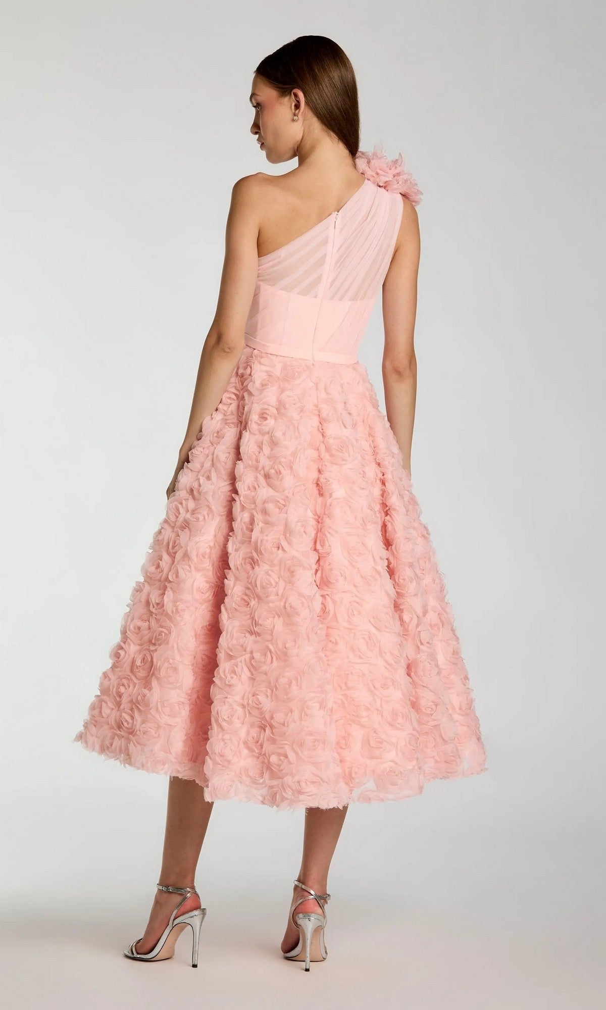A woman in the Midi Wine Wedding Guest Dress: Mac Duggal 27698, featuring a textured floral skirt and one-shoulder design, stands in profile with silver heels against a plain background.